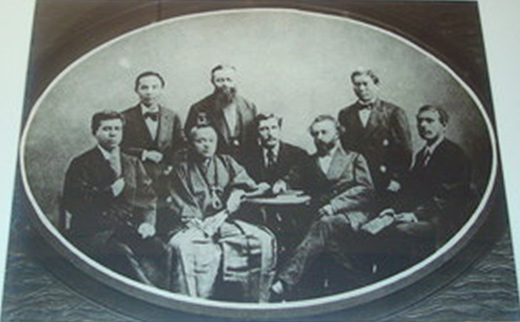 Framed photographic image of Iwakura Tomomi seated in traditional robe and surrounded by his Western hosts