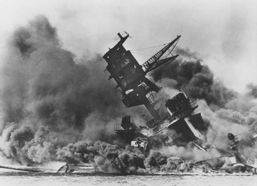 The forward superstructure and number two gun turret of the sunken USS Arizona afire after the attack on Pearl Harbor.